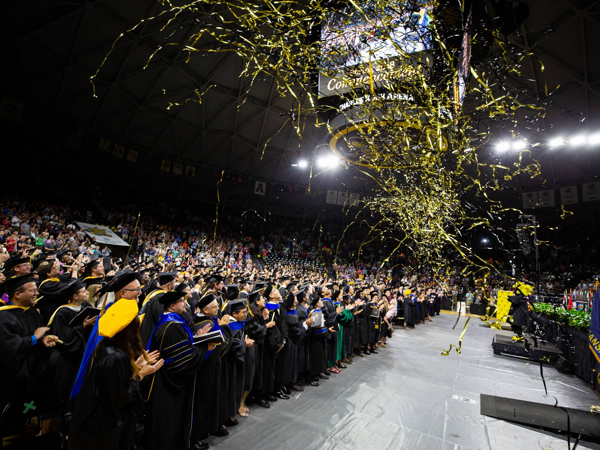 Graduates on the commencement floor at Charles Koch Arena