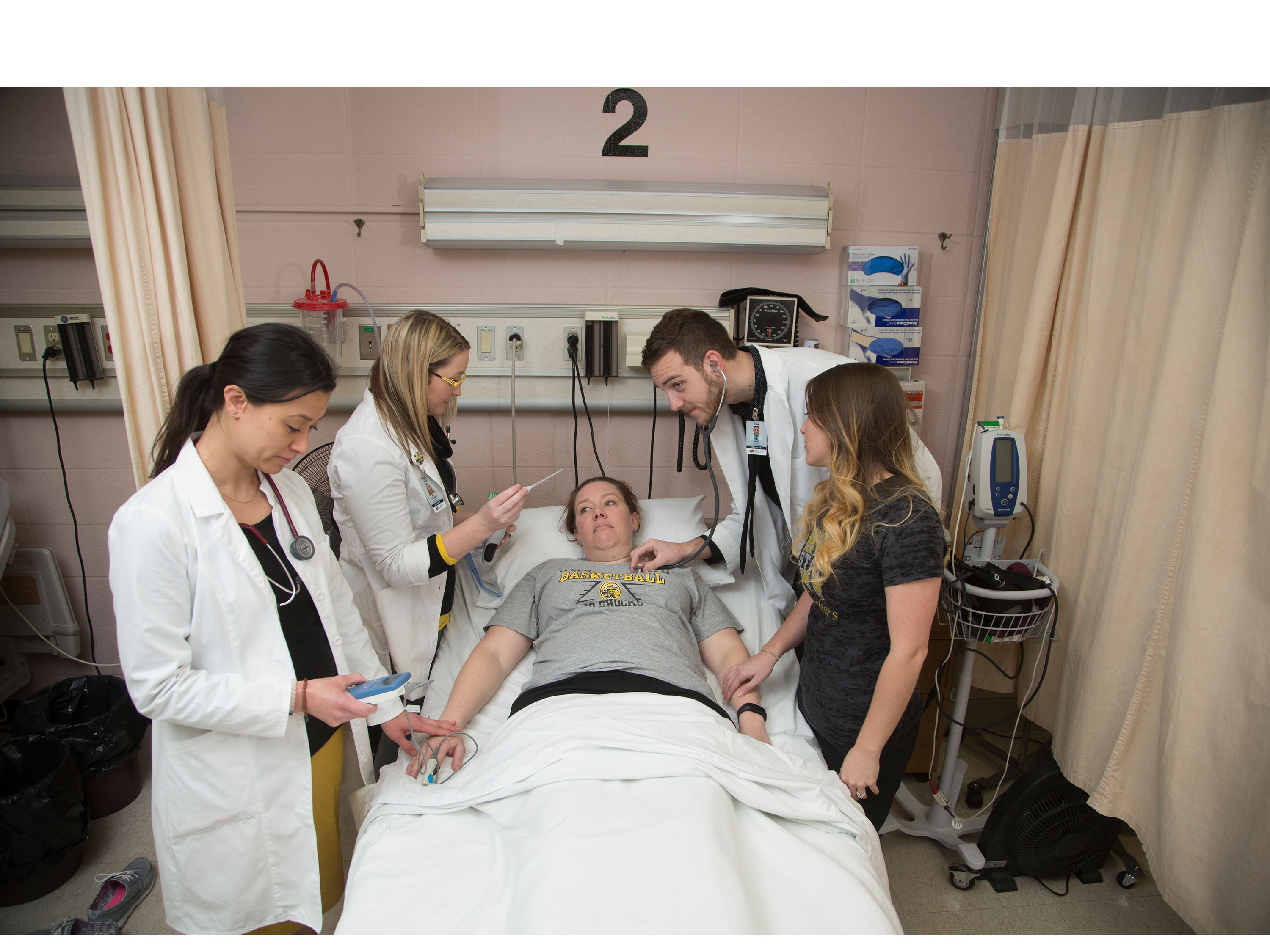 Nursing students exam a patient at bedside.