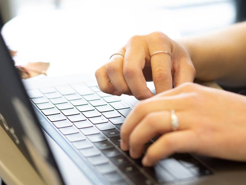 A photograph of hands typing on a computer keyboard. 