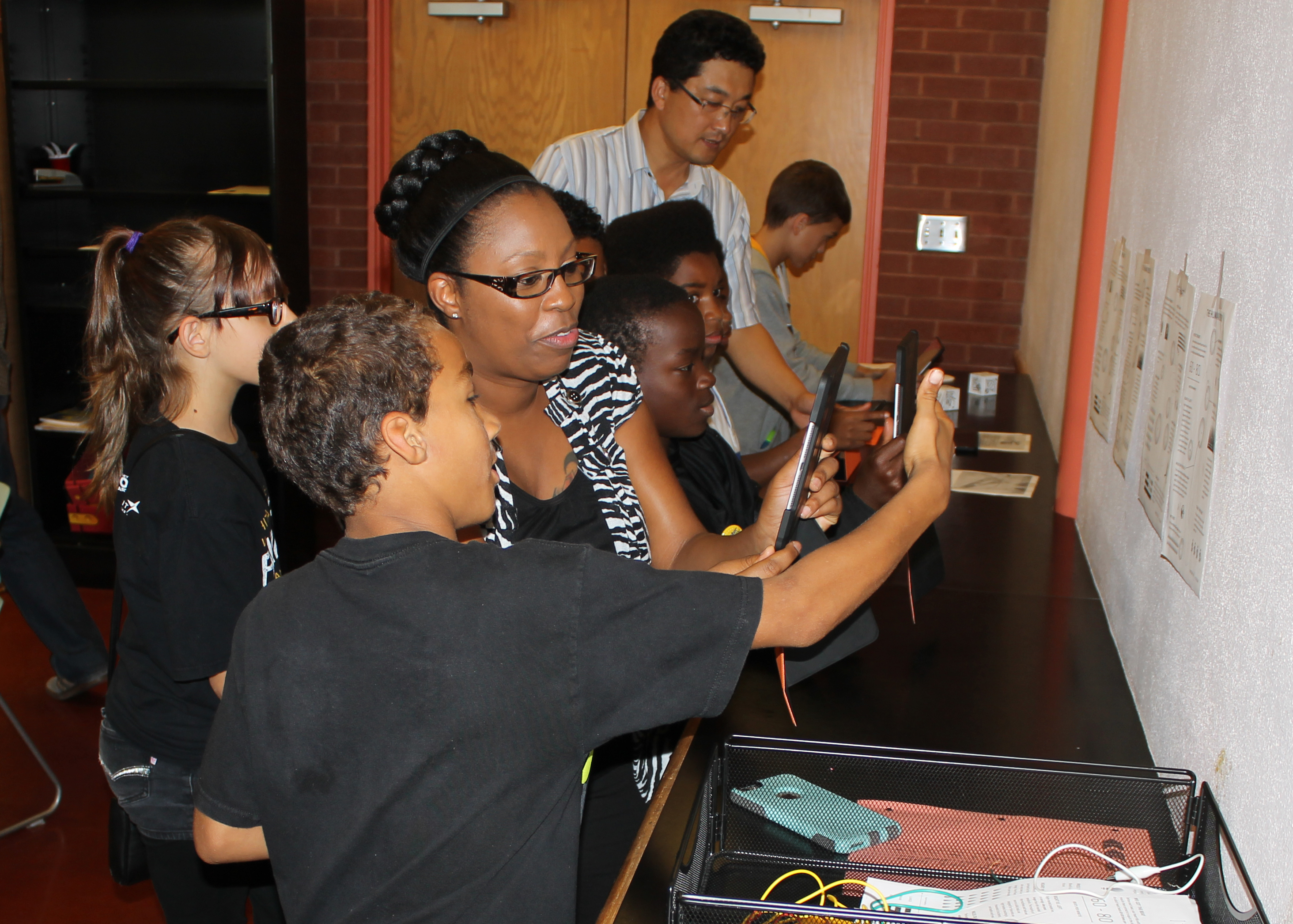 Students and a teacher look through a device.