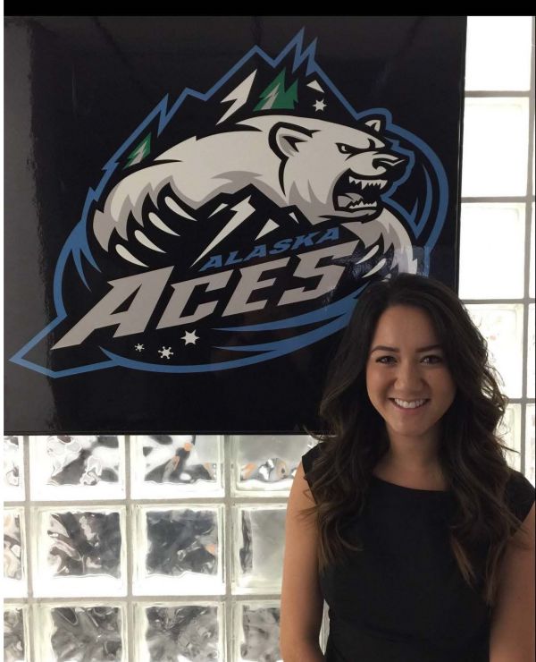 Student Chelsea standing in front of an Alaska Aces banner. 