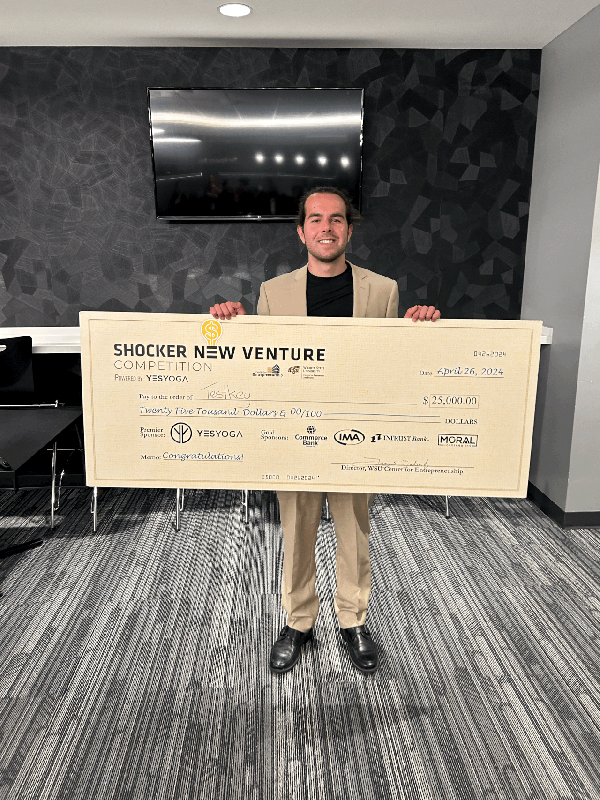 Nick Vasilescu posing with the giant check in the Champions Club of Koch Arena.