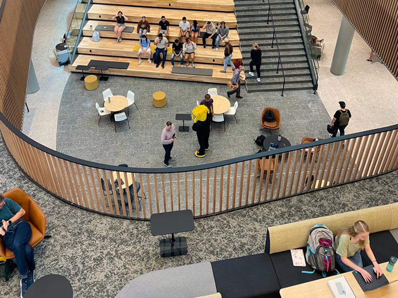 Some students lounge on the social stair in the Woolsey atrium while others study on the second floor