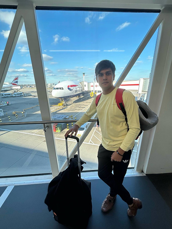 Akash Pandey stands in an airport with his luggage.