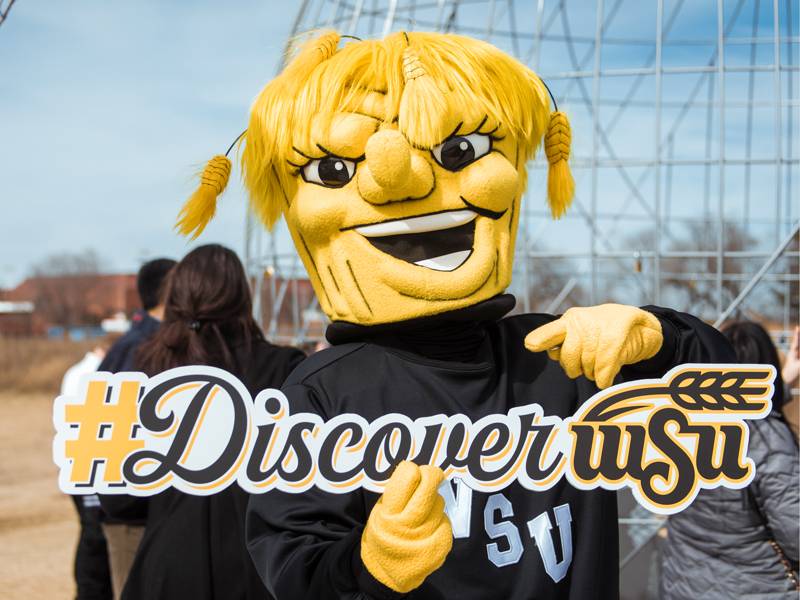 Wu holding up a Discover WSU sign
