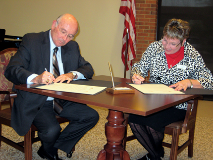 WSU President Donald Beggs, left, and Valerie McGhee, president of Larksfield Place Retirement Communities Inc., sign documents formalizing the alliance between the two entities.