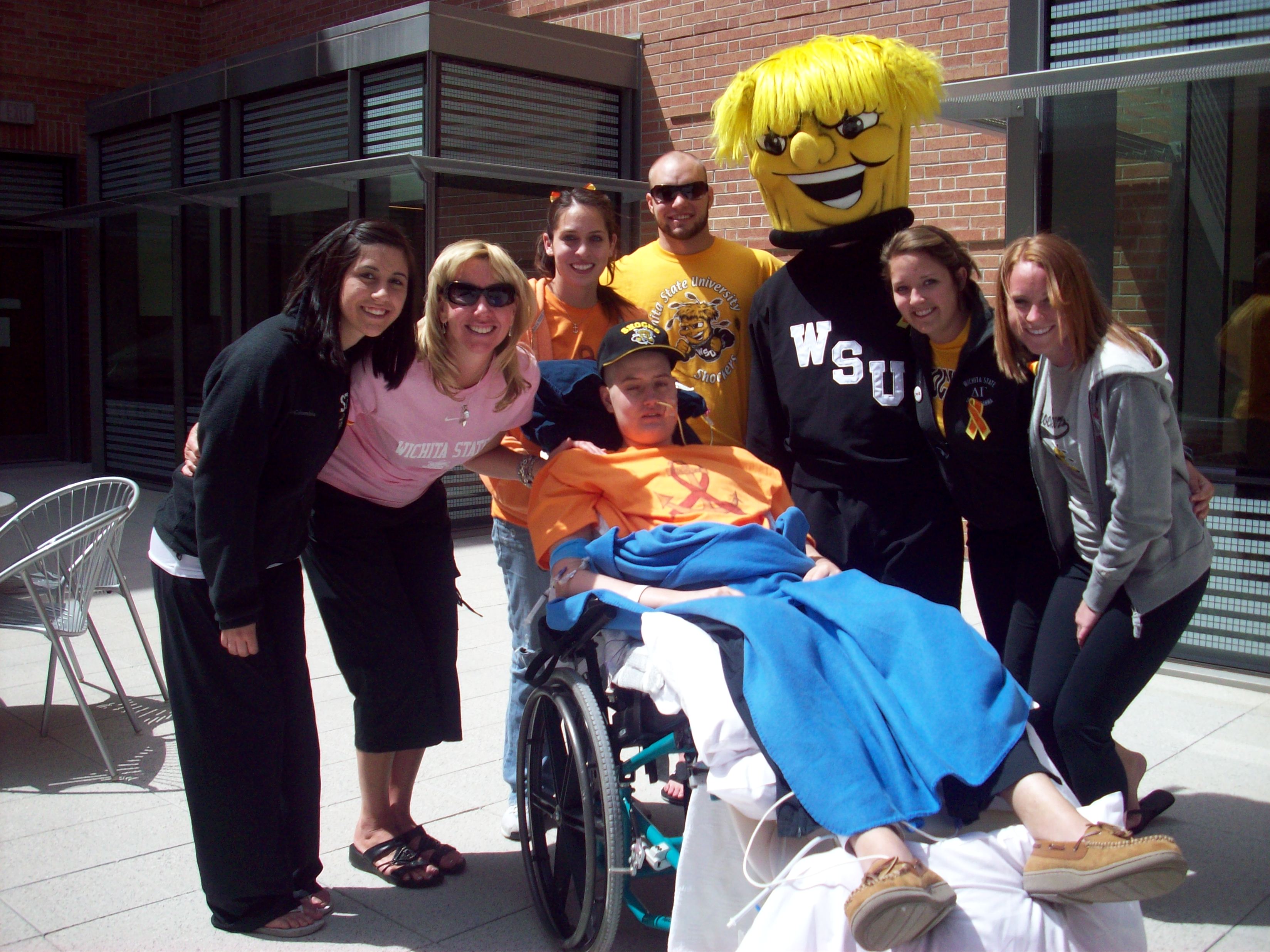 Zack Mesch is surrounded by WSU friends outside his hospital room. Pictured behind Mesch from l-r are Jody Oberthaler, Christine Schneikart-Luebbe, Megan Garcia, Ryan Floyd, WuShock, Kristen Luebbe and Liz Quinn.