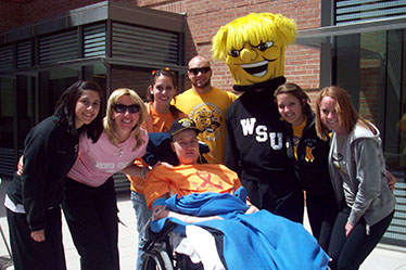 Zack Mesch is surrounded by WSU friends outside his hospital room. Pictured behind Mesch from l-r are Jody Oberthaler, Christine Schneikart-Luebbe, Megan Garcia, Ryan Floyd, WuShock, Kristen Luebbe and Liz Quinn.