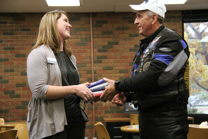 Sarah Sell, Student Success specialist and co-chair of the Veterans Advisory Board at Wichita State, accepts a donation of military flags from Ron Vangas, director of the American Legion Riders from Post 136, Mulvane, Kan.  The flags will be used to decorate WSU's new Military and Veteran Student Center.