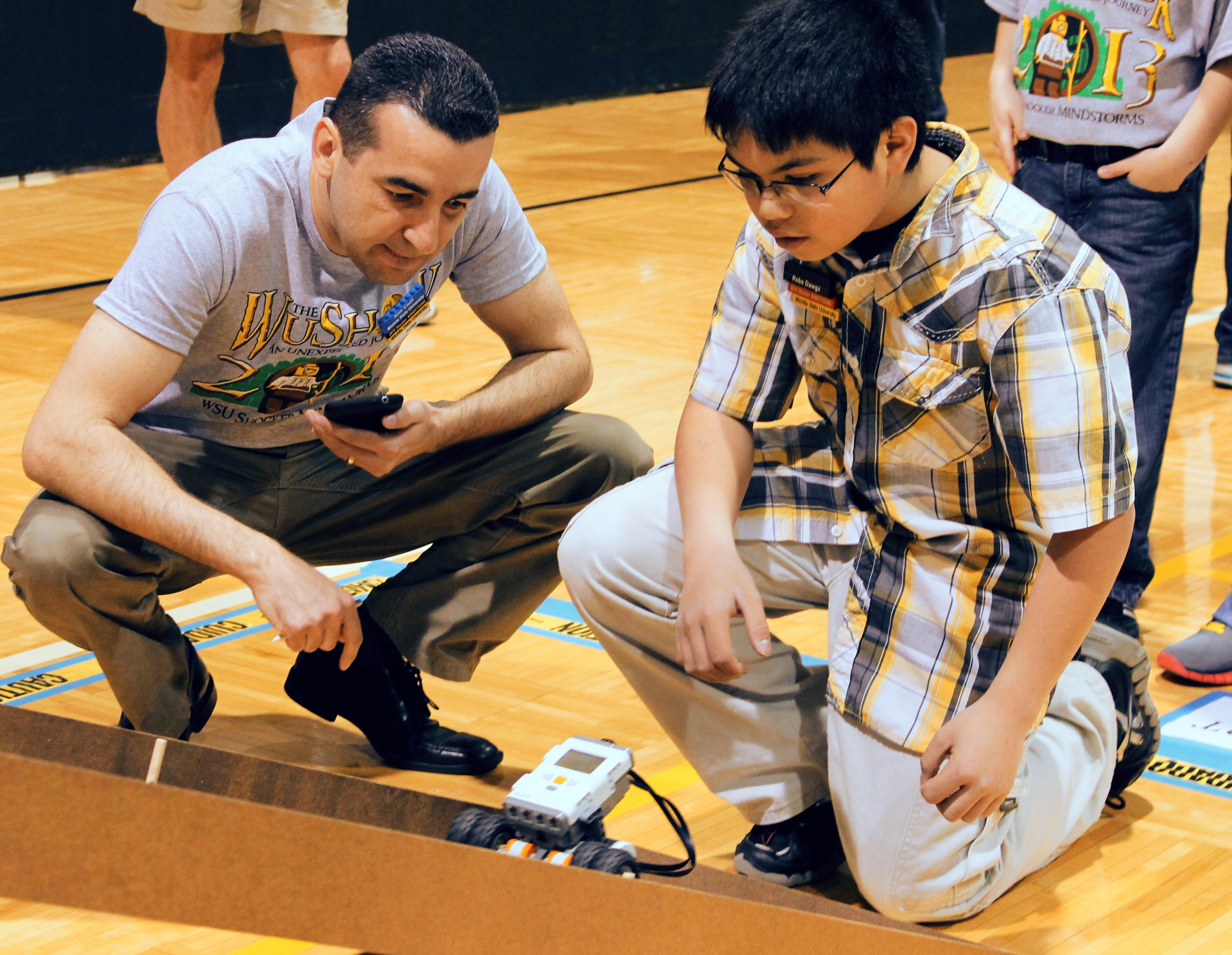 Kim Cluff, assistant professor of bioengineering, and a student competitor watch as a LEGO Mindstorms robot attempts to complete a course challenge during the 2013 LEGO Mindstorms Challenge.