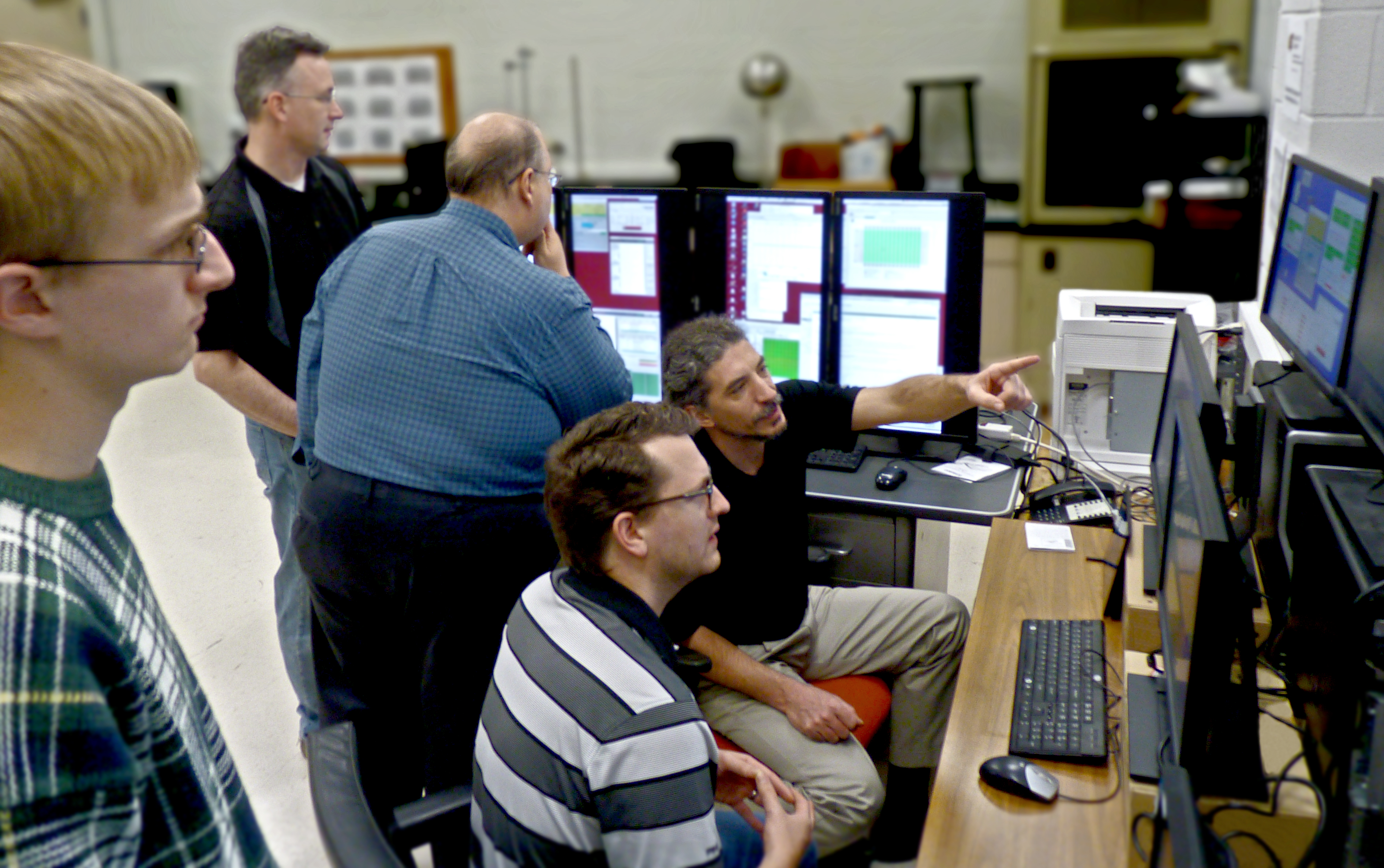 WSU physics professors and students watch data stream in at the NOvA experiment control center in the basement of Jabara Hall in December 2014. From left: WSU student Conner Ubert, Information System Specialist Mark Arrasmith, Professor Nick Solomey, Assistant Professor Mathew Muether and Associate Professor Holger Meyer., WSU physics professors and students watch data stream in at the NOvA experiment control center in the basement of Jabara Hall in December 2014. From left: WSU student Conner U