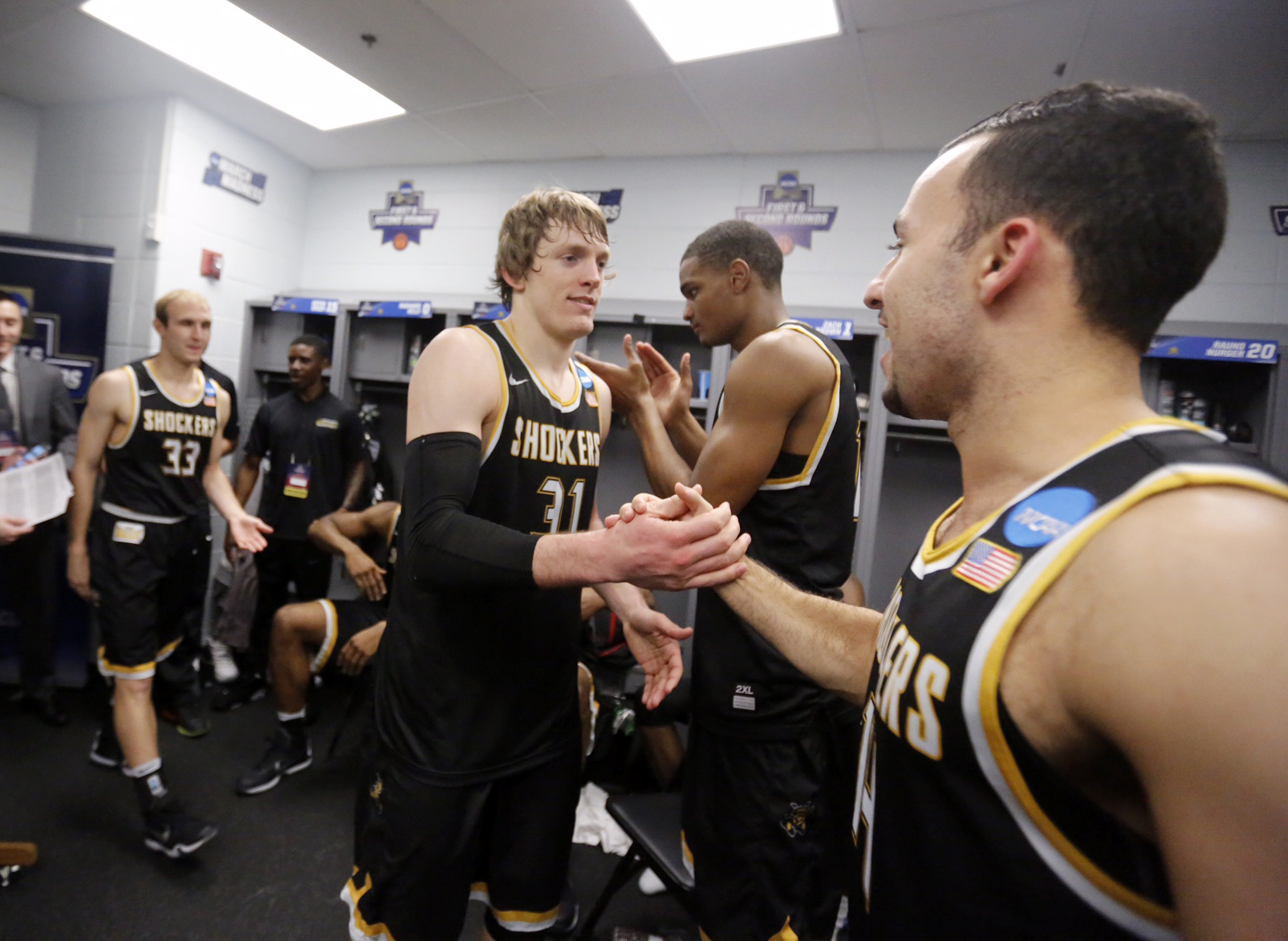 Ron Baker, center, is congratulated by teammate J.R. Simon following WSU's 65-55 win over Arizona in the NCAA Tournament First Round.