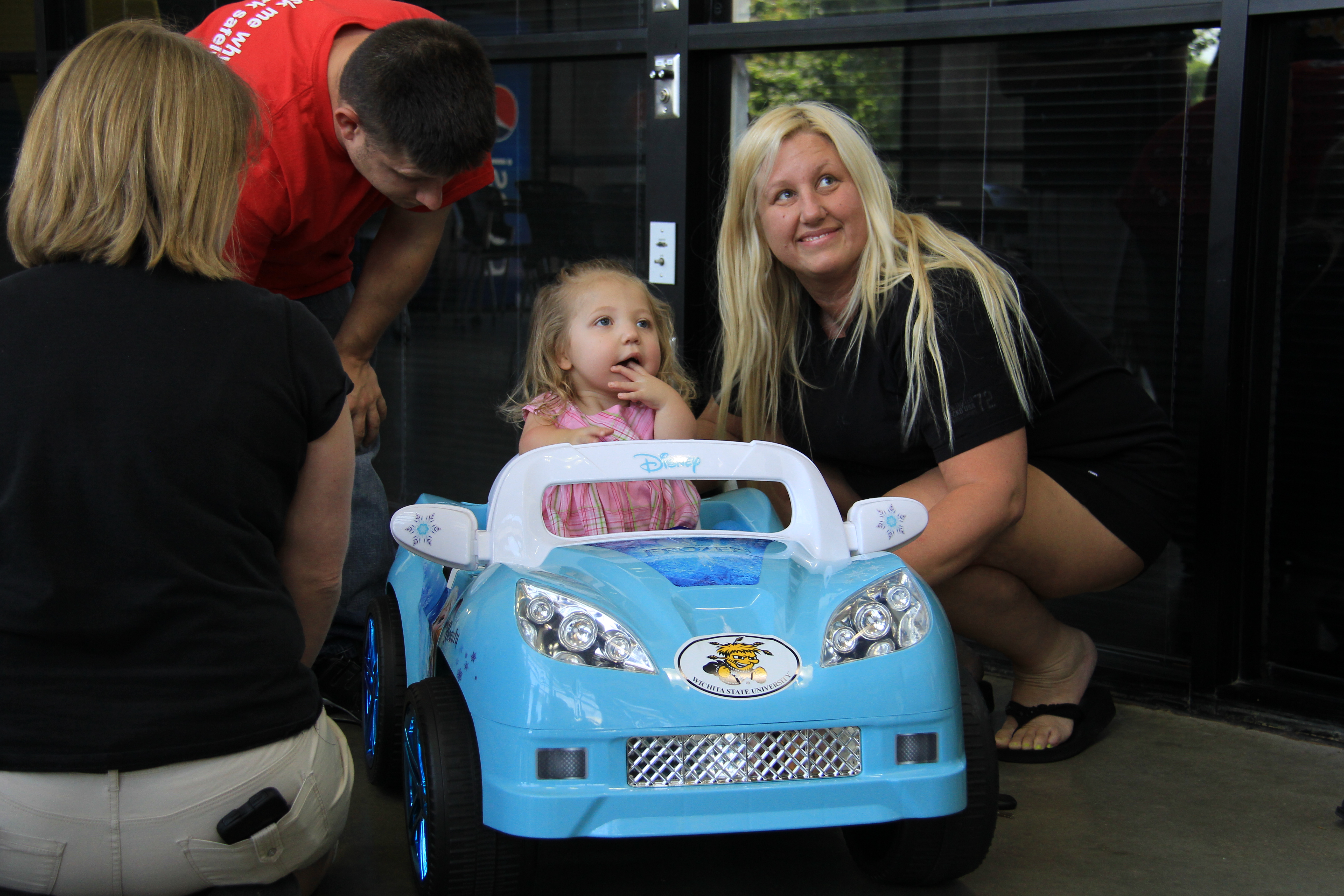 Jocelyn McNeese gets familiar with her ride-on toy car, modified for her needs by Wichita State's GoBabyGo! group.