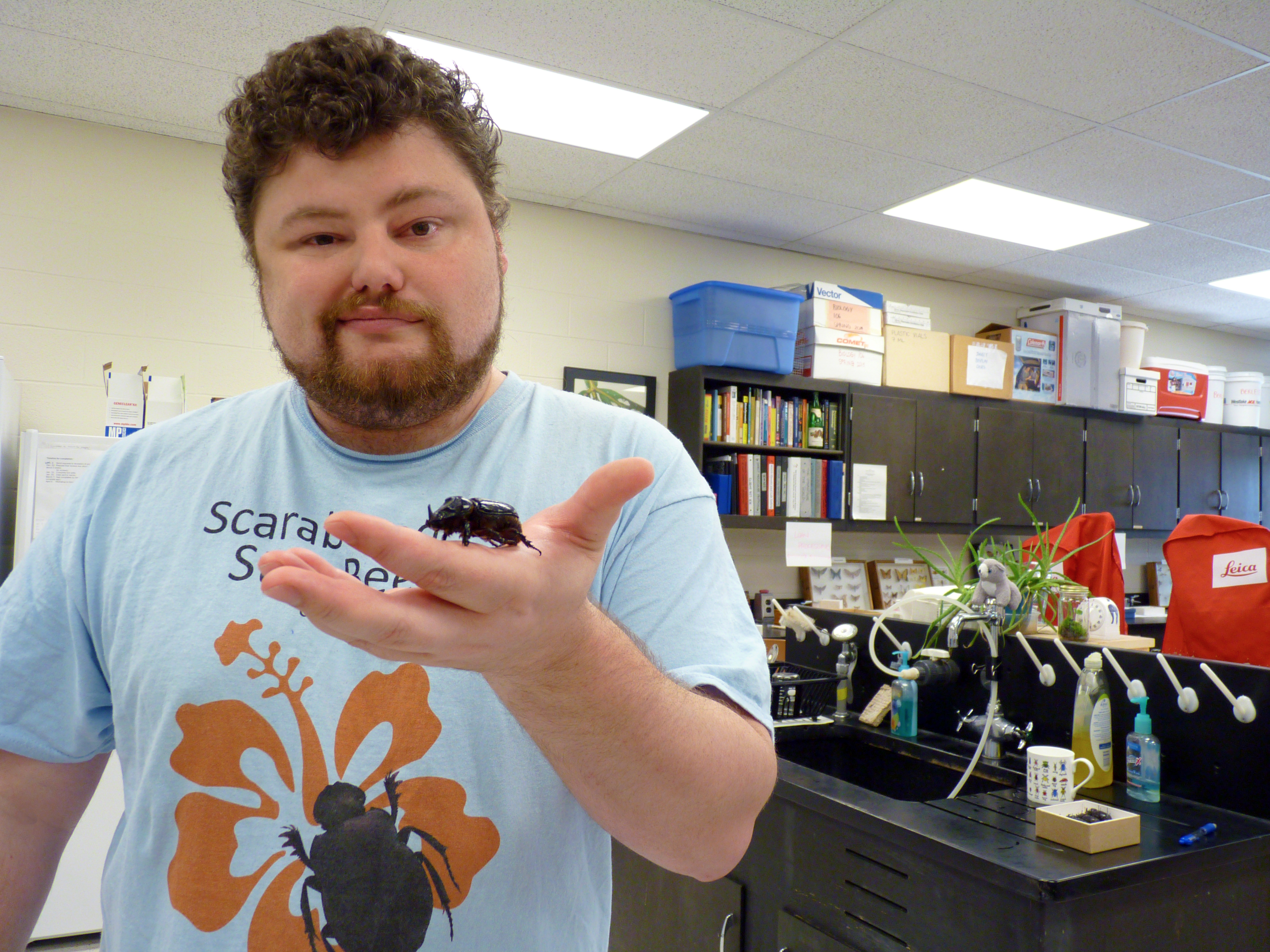 WSU student Josh Dunlap with a coconut rhinoceros beetle.