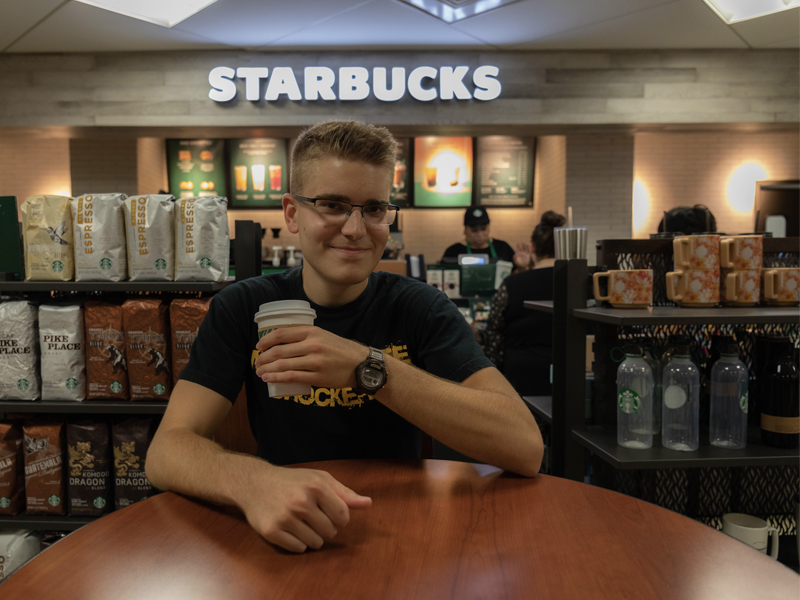 Andrew Martin, marketing intern, enjoys a cup of coffee at the Starbucks in the Rhatigan Student Center.