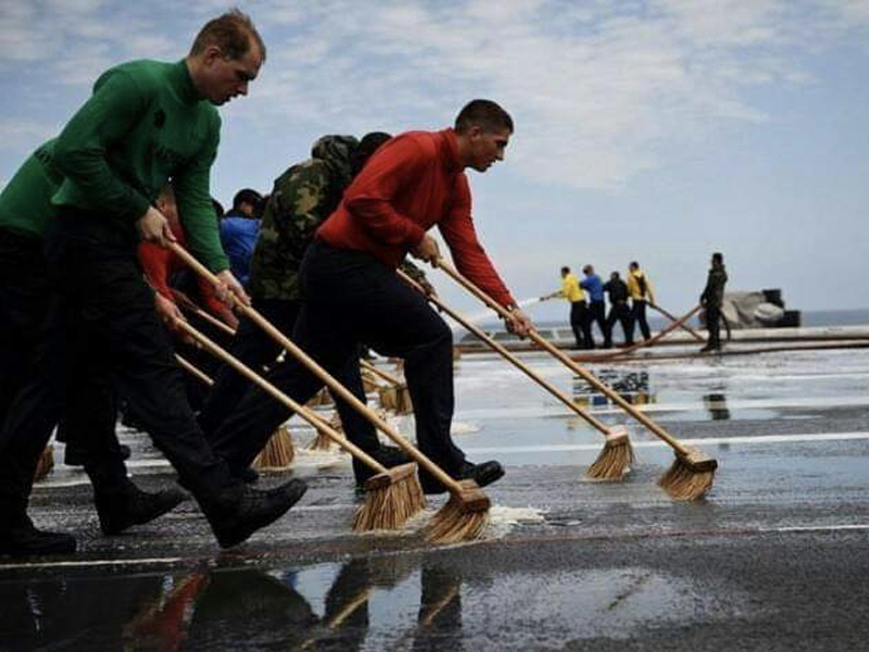 Jonathan, in red, leads a team of sailors in a foreign object and debris sweep on the deck of the Reagan.