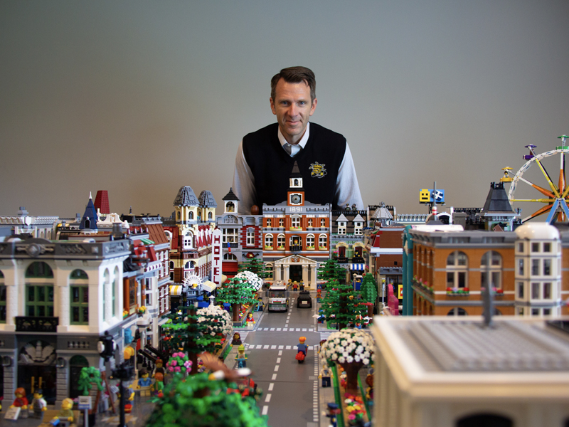 Dennis Livesay stands behind his LEGO city, overlooking the city hall and main boulevard