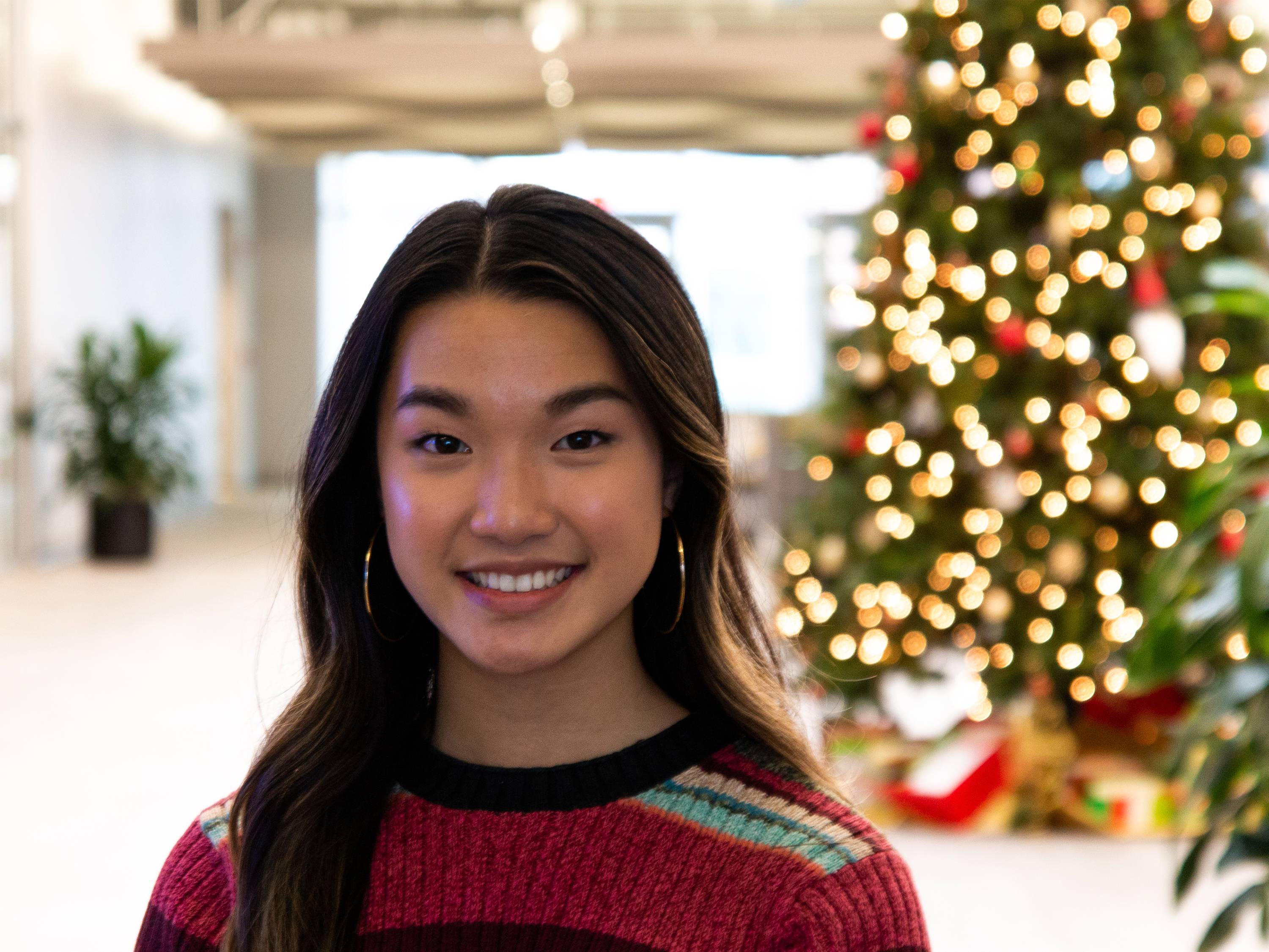Stella Yang, economics grad, stands near the holiday foliage in the Airbus Wichita State lobby
