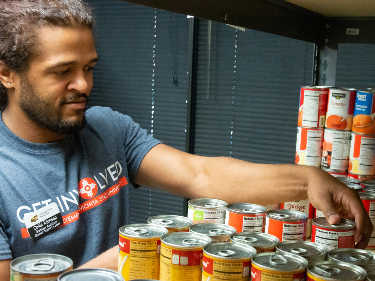 Colin Munson, Shocker Support Locker graduate assistant, arranges canned items in the locker