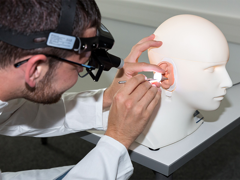 audiology student examines simulation manikin