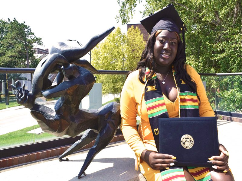 Aunjnae White, a first-generation student, posing with her degree in psychology.