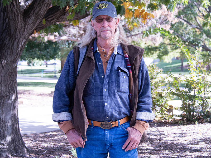 Eric Harrison stands, hands in his pockets, outside of Morrison Hall