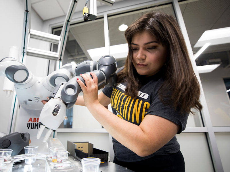 A student workign with a robotic arm