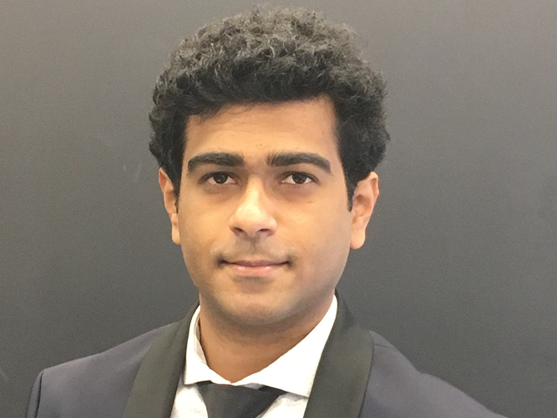 Manoj Krishnamaraja dressed in a suit against a grey background.