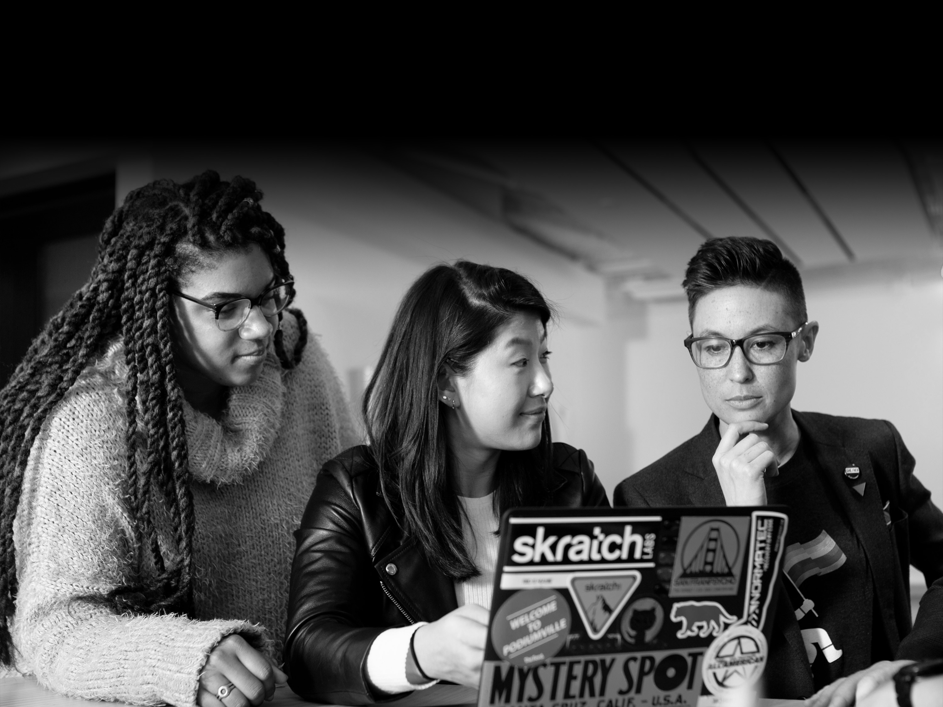 Three peopling at a computer talking.