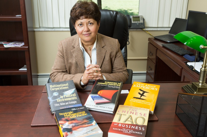 Usha Haley at a desk, with a series of books.