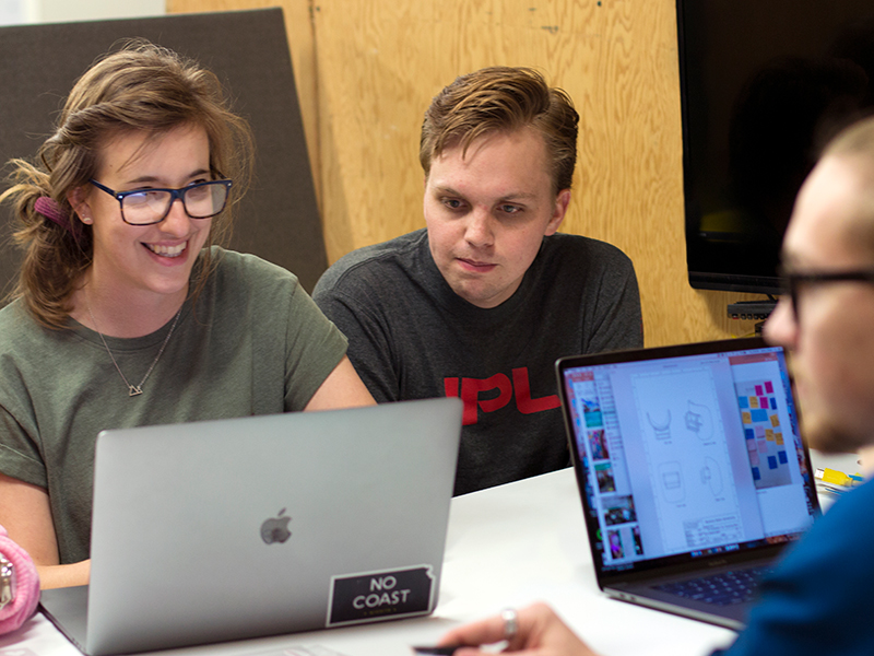 Master of innovation design students working together over a laptop.