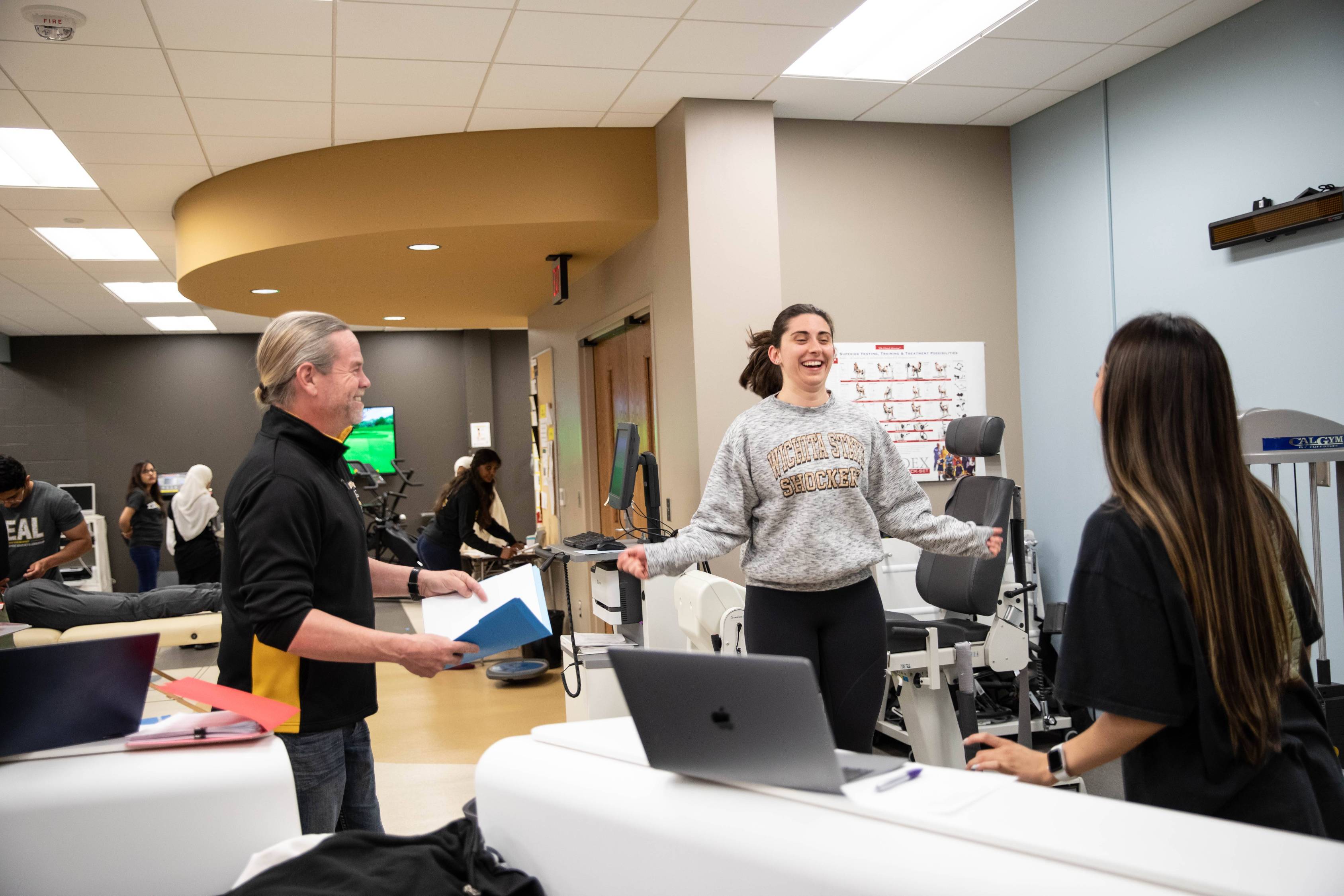 Student jumping rope in Human Performance Lab while faculty supervises and reviews notes.