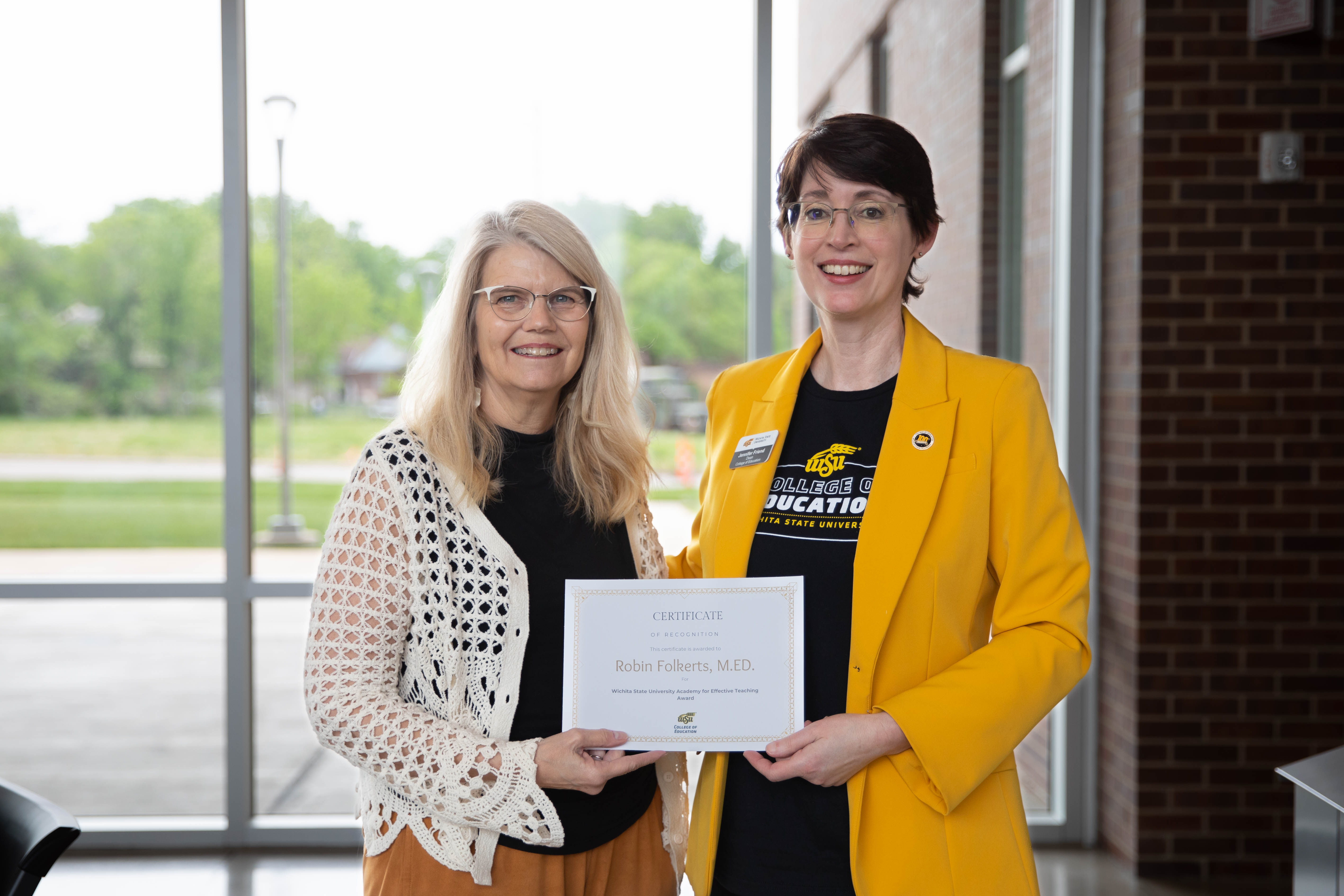 Robin Folkerts holds a teaching award certificate while standing with Dr. Jennifer Friend, dean of the College of Education.