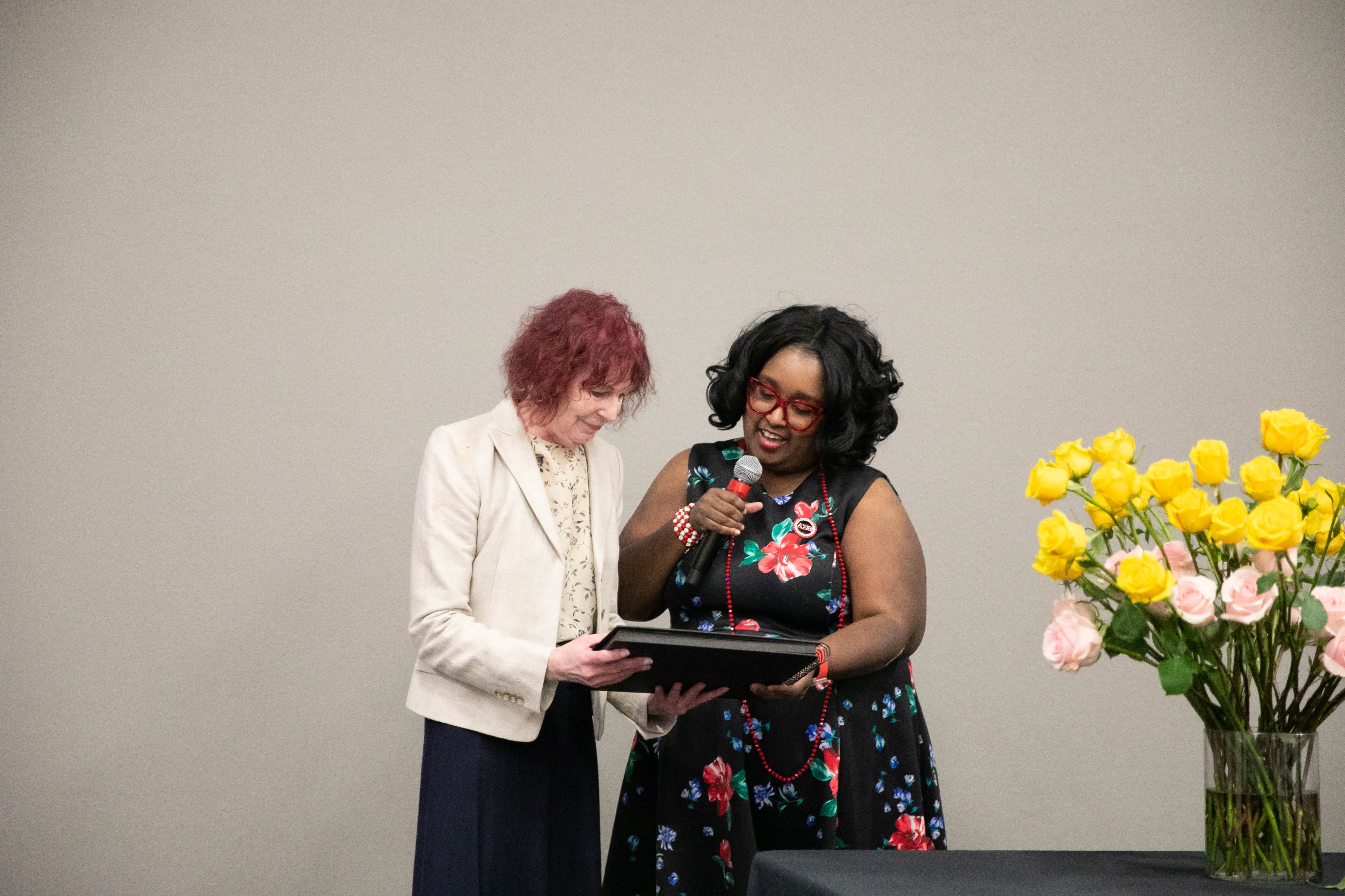 Dr. Jean Patterson reviews a recognition gift alongside Dr. Valerie Thompson during the Wichita State University educational leadership EdD program spring 2026 luncheon.