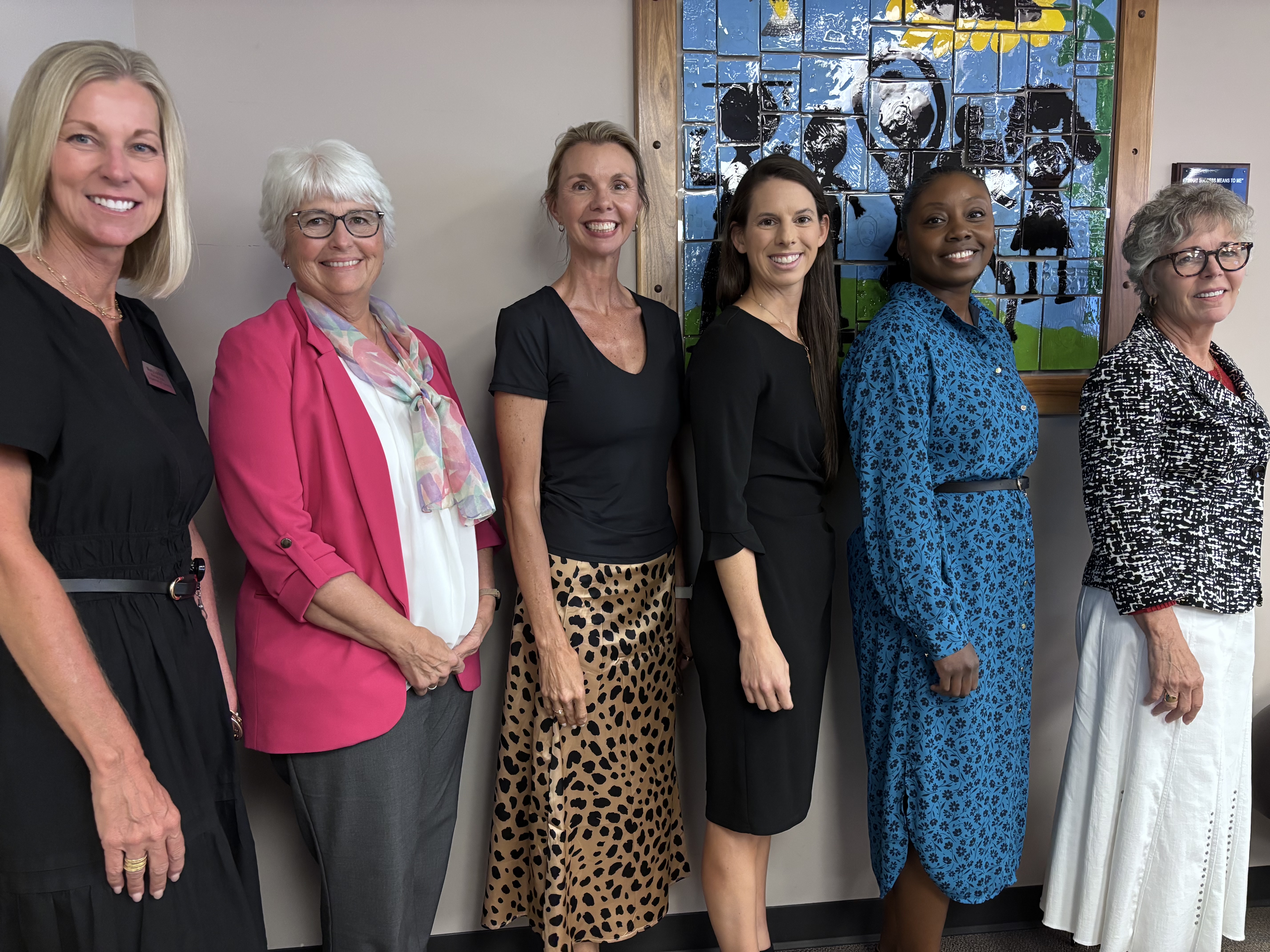 Left to right: Mary Lonker, English Language Arts (ELA) Program Manager for Teaching and Learning at the Kansas State Department of Education (KSDE); Dr. Laurie Curtis, Assistant Director of Teaching and Learning – Structured Literacy at KSDE; Dr. Kim Moody, Professor and Coordinator of MAT ECU/EEU, Reading Specialist and Structured Literacy Coordinator, and Director of CLEAR; Dr. Reagan Murnan, Assistant Professor of Special Education; Dr. Sherrie Frazey, Executive Director of School Support and Improvement for Wichita Public Schools; and Dr. Cindy Lane, Director of the Kansas Blueprint for Literacy. Six women stand together indoors in front of a colorful stained-glass artwork, smiling at the camera.