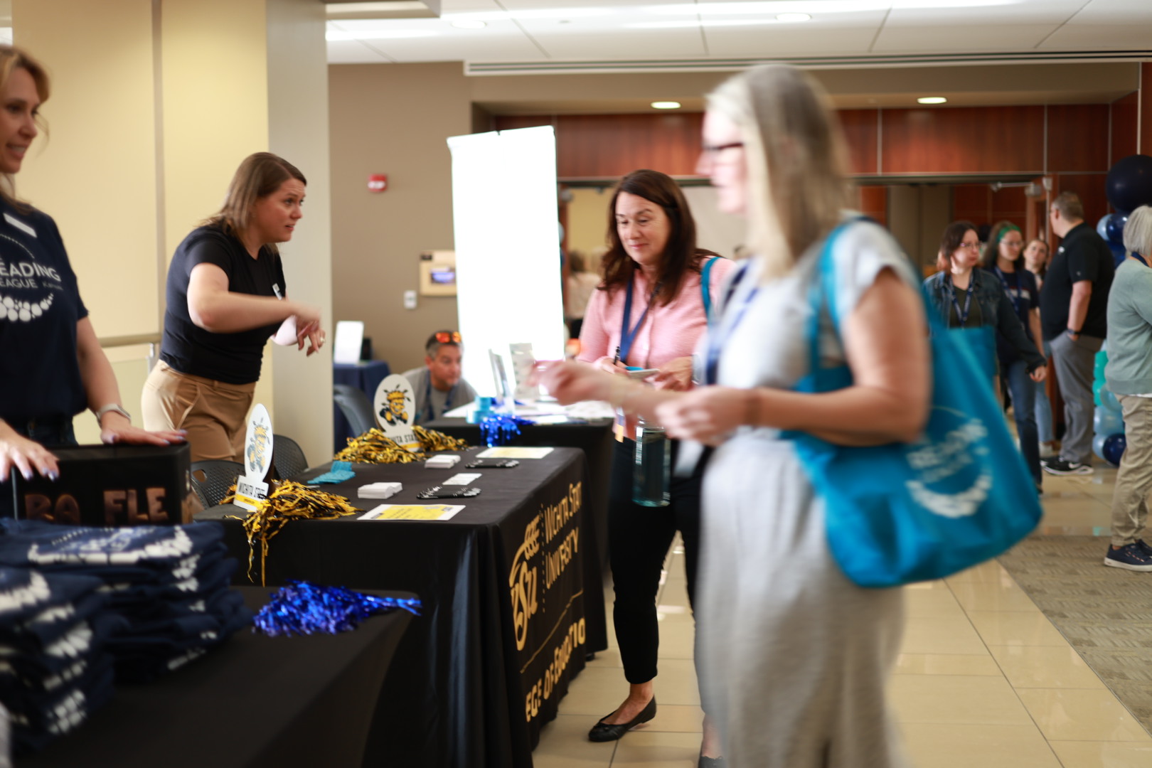 Attendees interact with staff at a resource table during a literacy conference