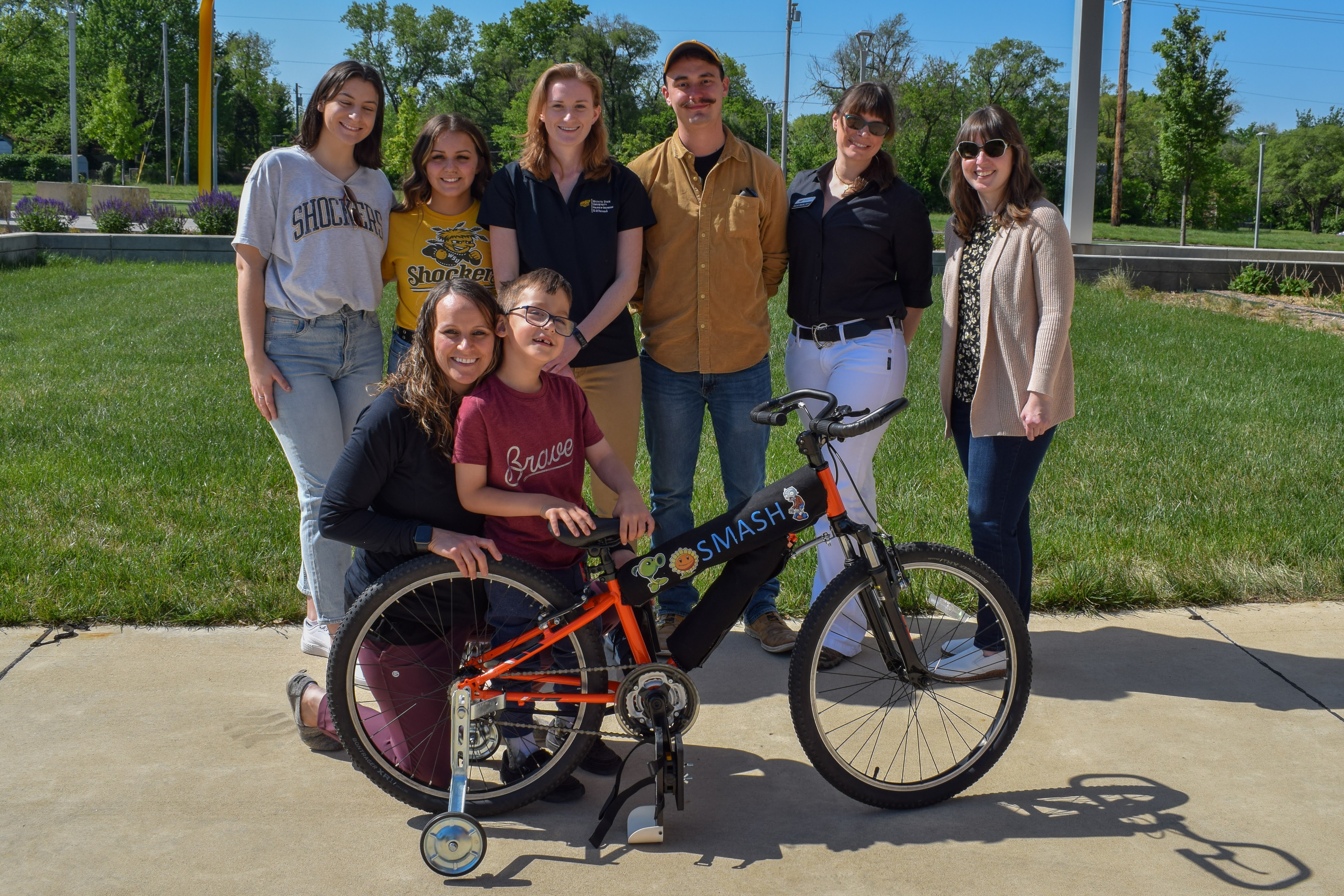 Team of students and faculty with a client who is riding a bike for the first time