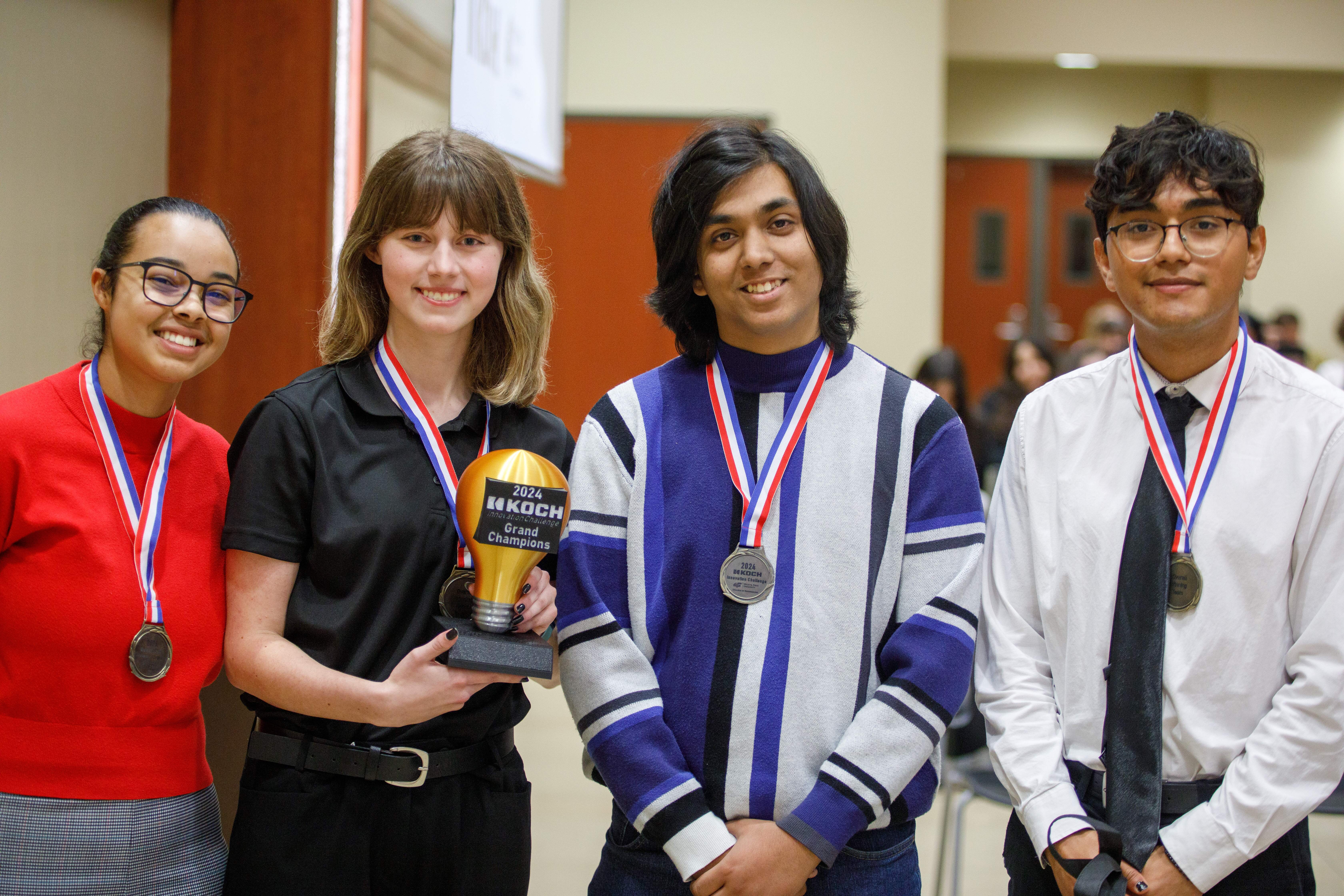 Four students stand with their trophy from the competition.