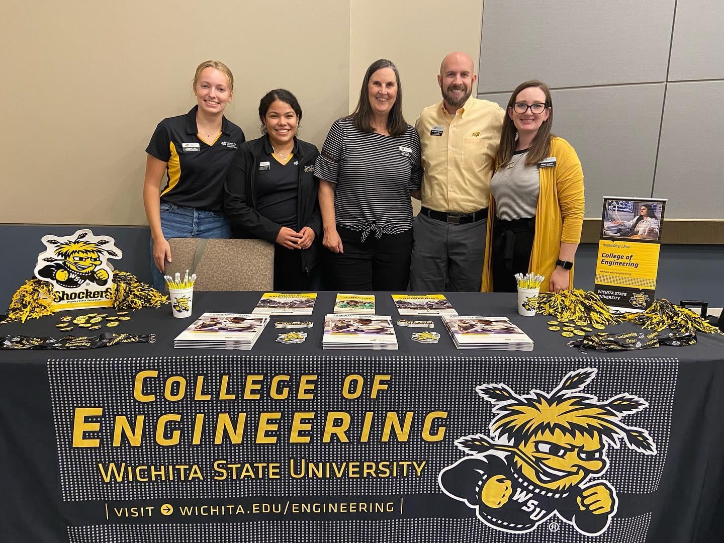 College of Engineering Staff and CoESA members stand behind a table at an event