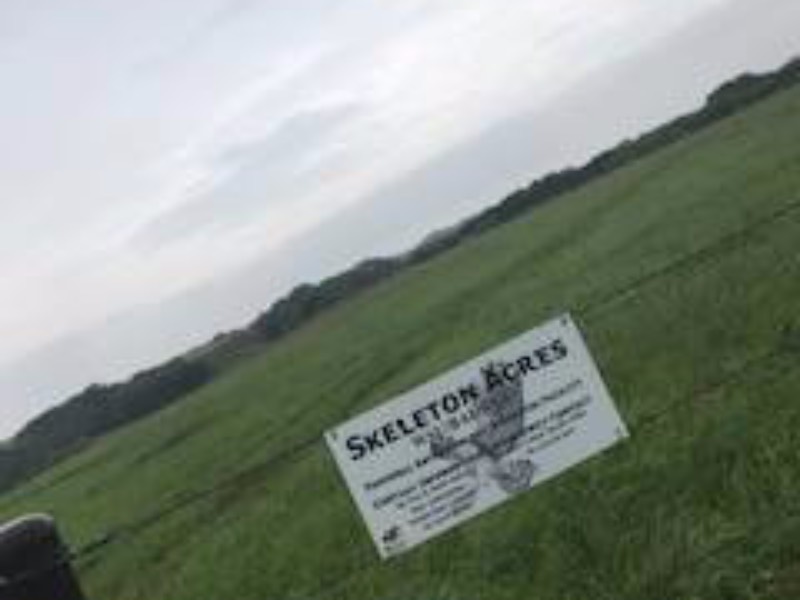 "Skeleton Acres" sign in an open field