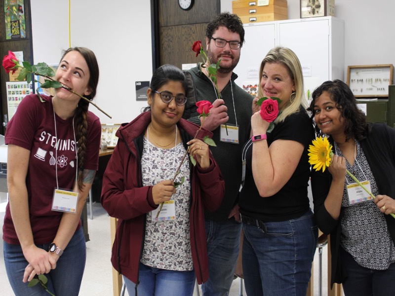 group of graduate students posing with roses