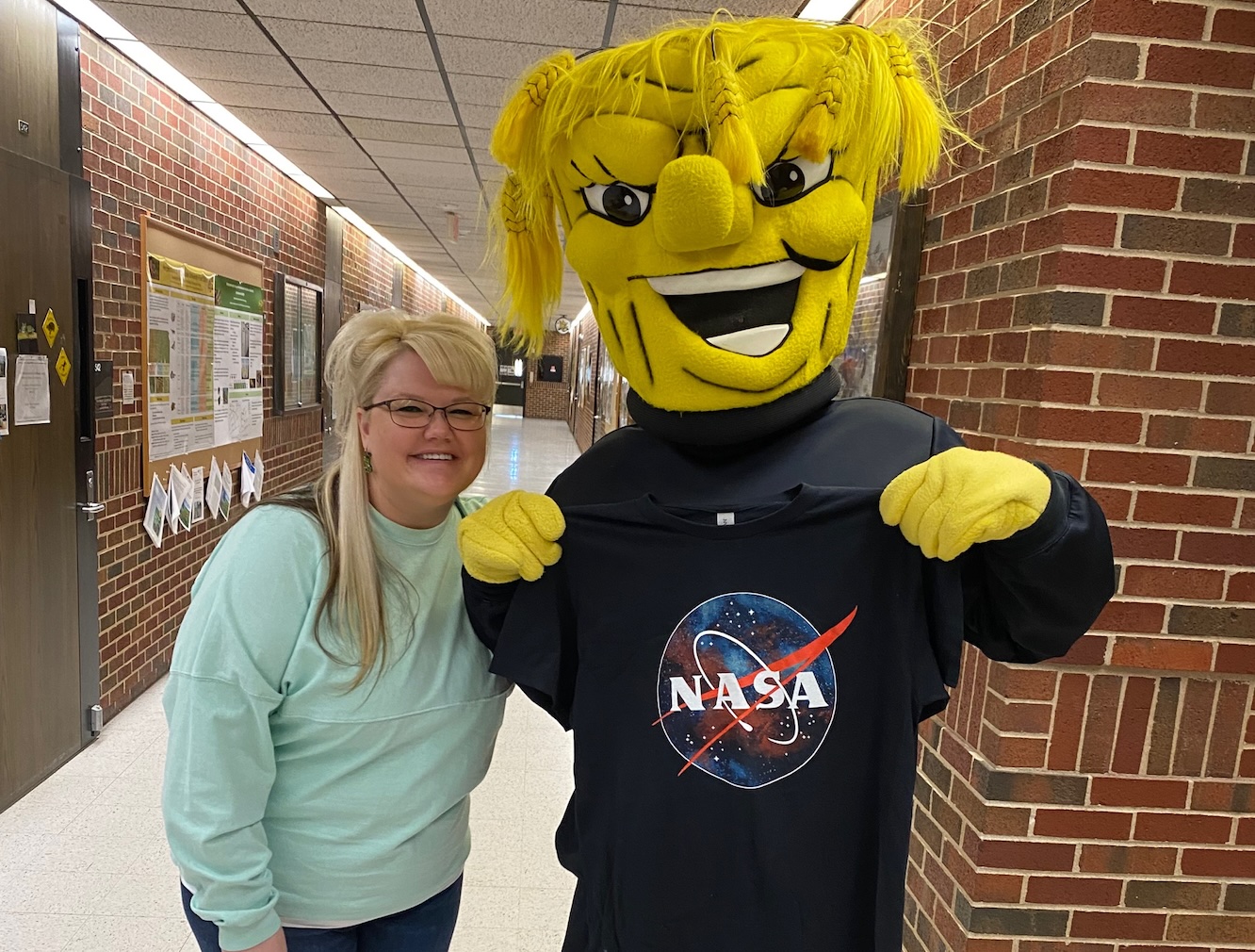 Photograph of seminar speaker with Wushock, who is holding a NASA shirt over his chest