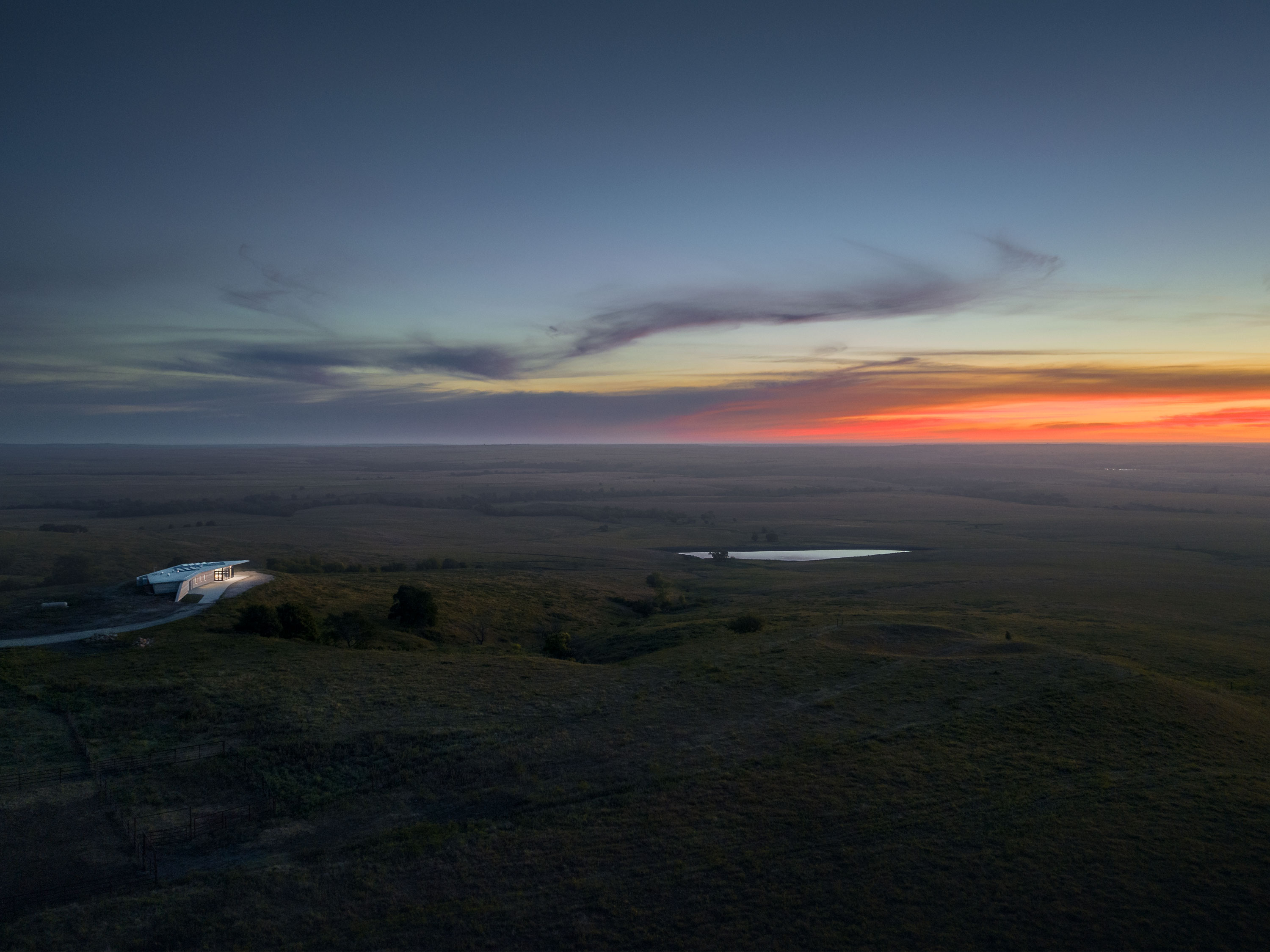 Overhead view of Youngmeyer Ranch Reserve at sunset, with pink and orange skies on the horizon and a large vista of fields. Photo by Hutton Design+Build.