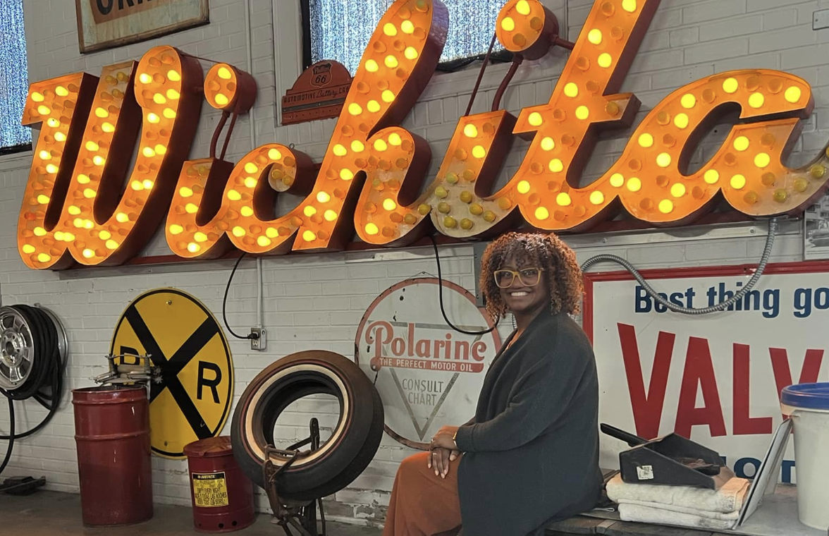 Ricki Ellison in front of a Wichita sign