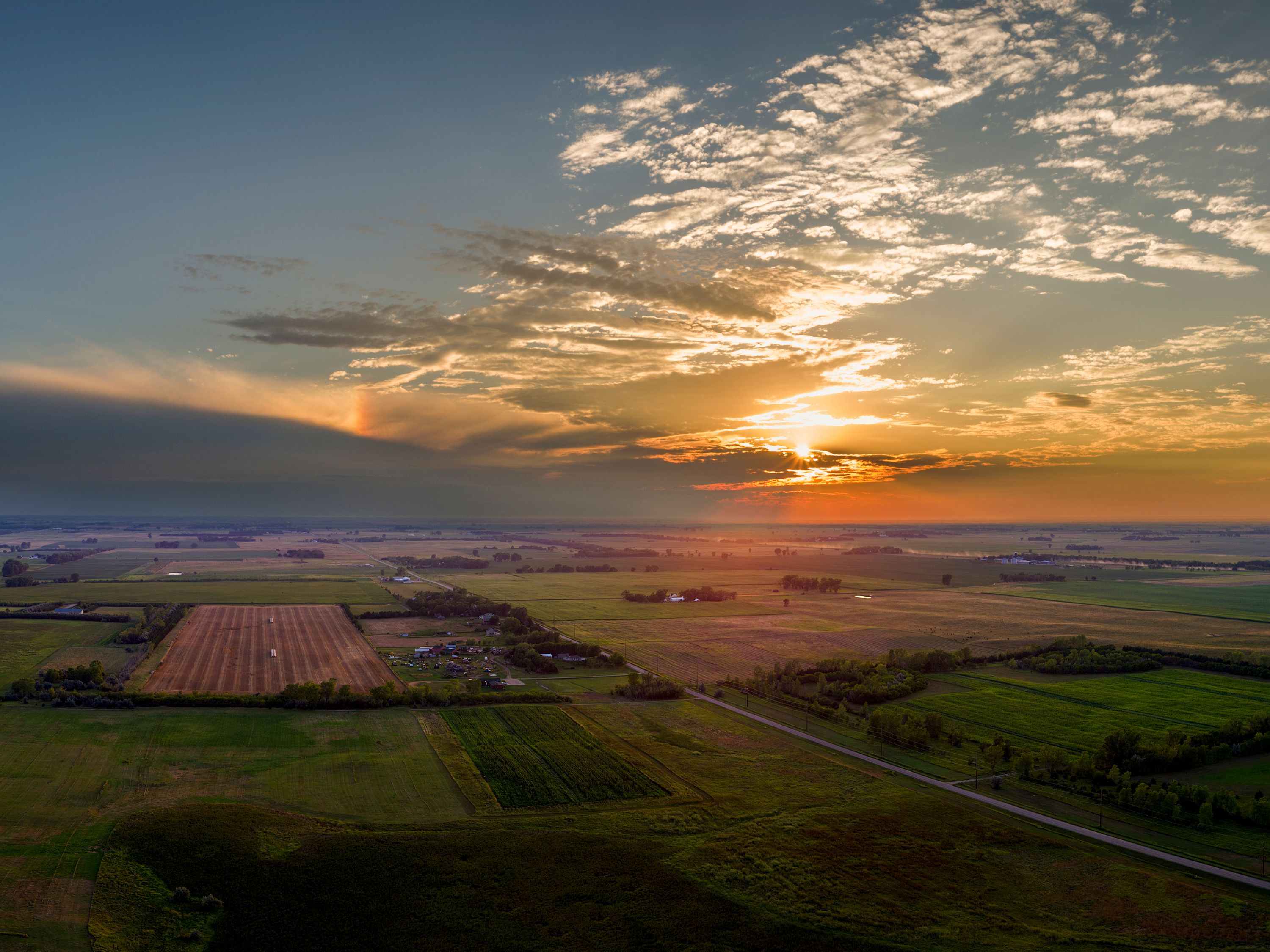 an aerial view of the sun setting over a field