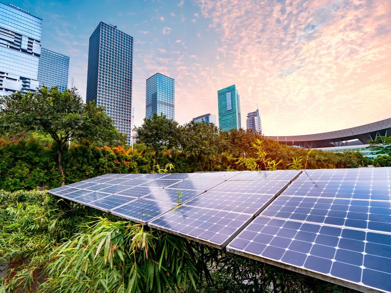 photo of city buildings and infrastructure with greenery and solar panels 