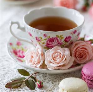 Photo of a fancy cup of tea with pink roses and macarons