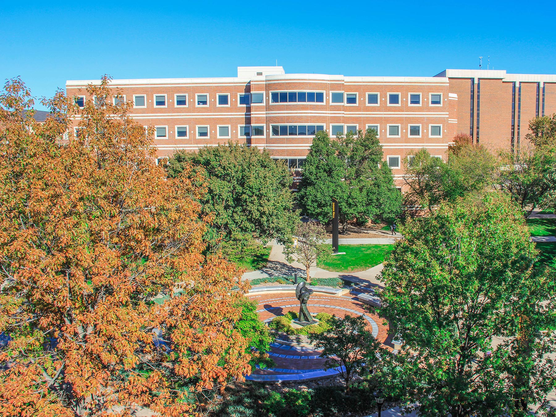 alt="Jabara Hall appears above trees with fall foliage"