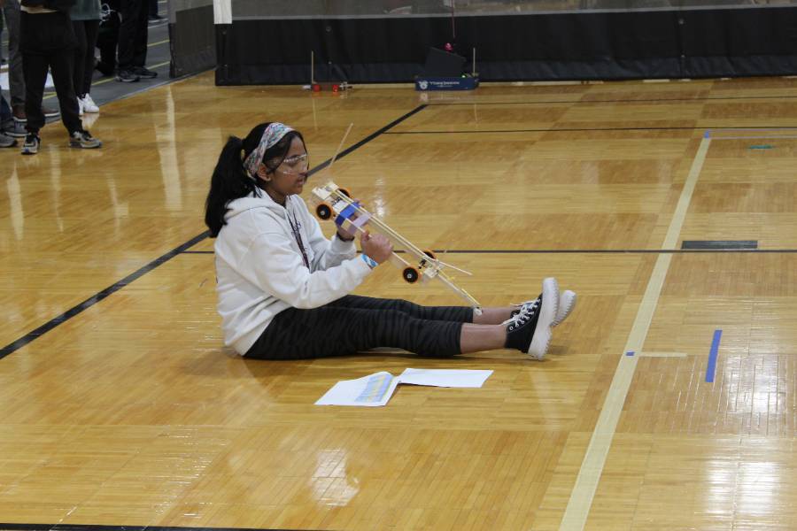 A student examines her team’s wheeled vehicle during the state competition in April 2023. 