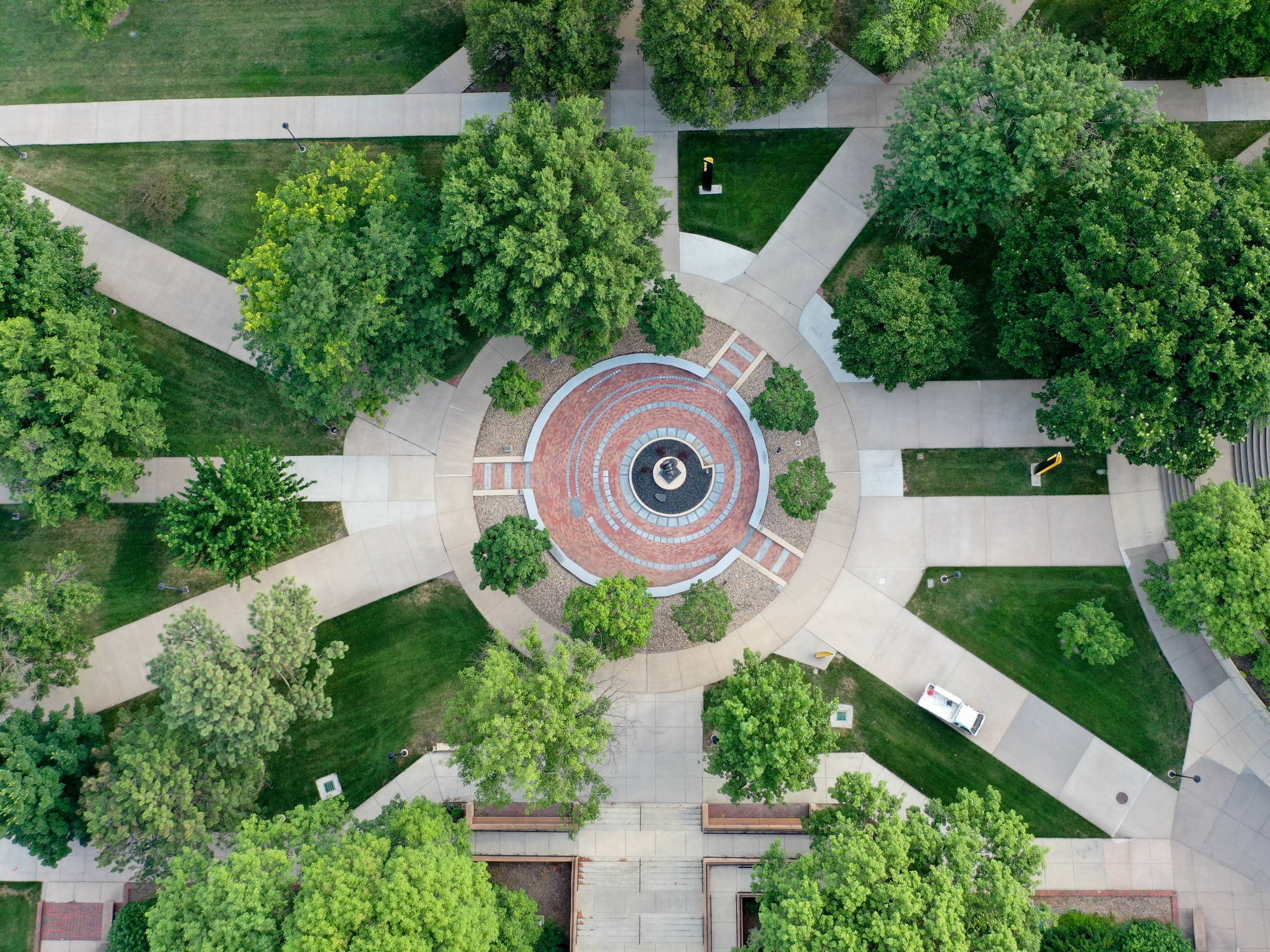 Ariel view of the Plaza of Heroines. Bronze sculpture slightly off-center in a circular plaza constructed with engraved bricks and granite pavers. Engraved granite benches outline the space.